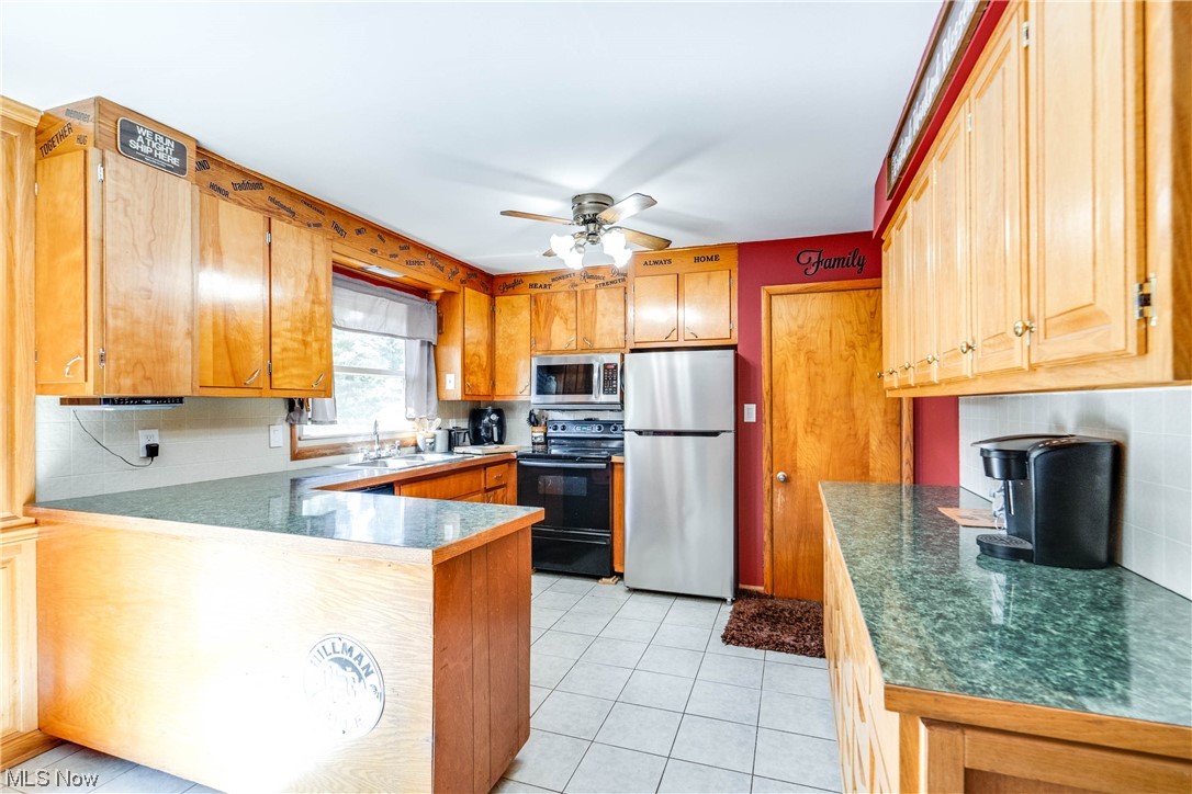 7384 Clark Road Atwater, OH 44201 - Photo 4 of 26 Kitchen brown cabinets, light tile floors, ceiling fan, stainless steel appliances counters