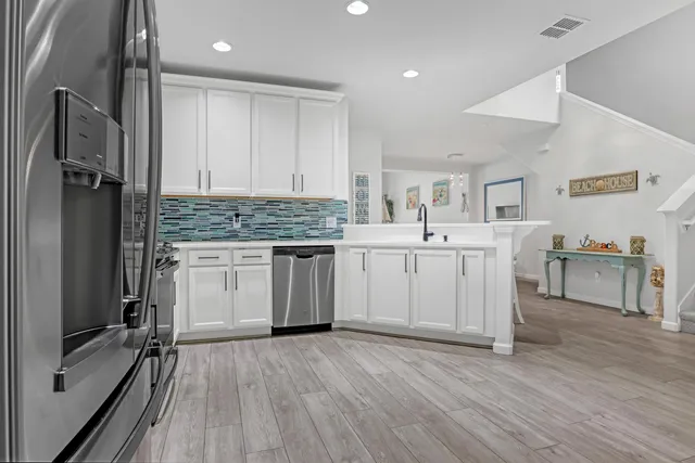 a large white kitchen with cabinets a sink and stainless steel appliances