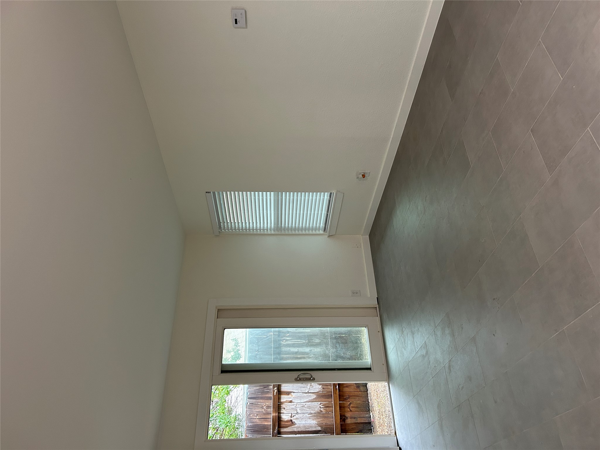 6502 South 1st Street, Unit 101 Austin, TX 78745 - Photo 12 of 12 Spacious room featuring large format tile flooring, white baseboards, and a sliding glass door providing exterior access