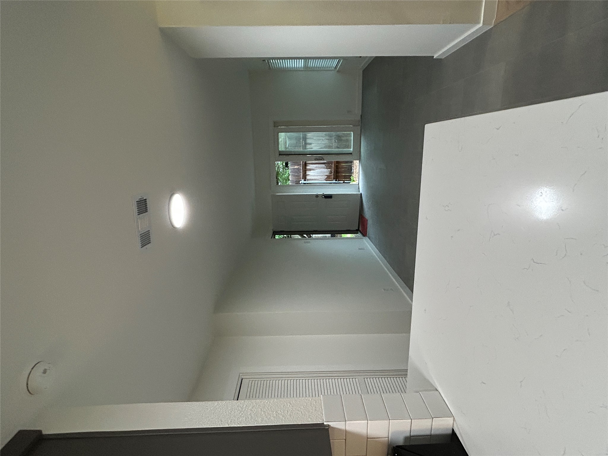 6502 South 1st Street, Unit 101 Austin, TX 78745 - Photo 5 of 12 Open-concept living space featuring a white countertop, subway tile backsplash, and light gray flooring