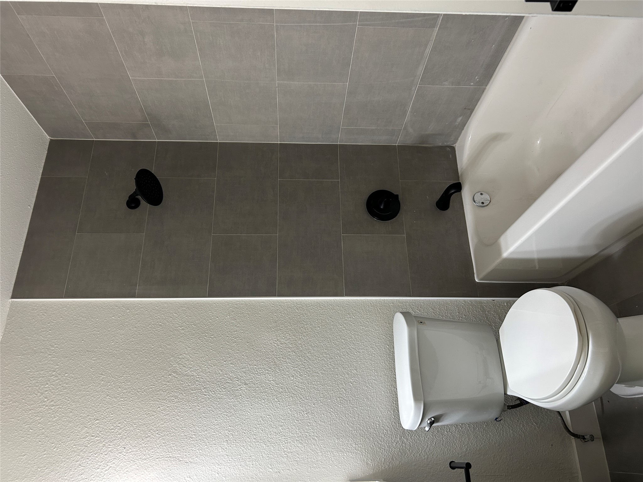 6502 South 1st Street, Unit 101 Austin, TX 78745 - Photo 6 of 12 Bathroom featuring a white bathtub, gray rectangular wall tiles, and matte black shower fixtures