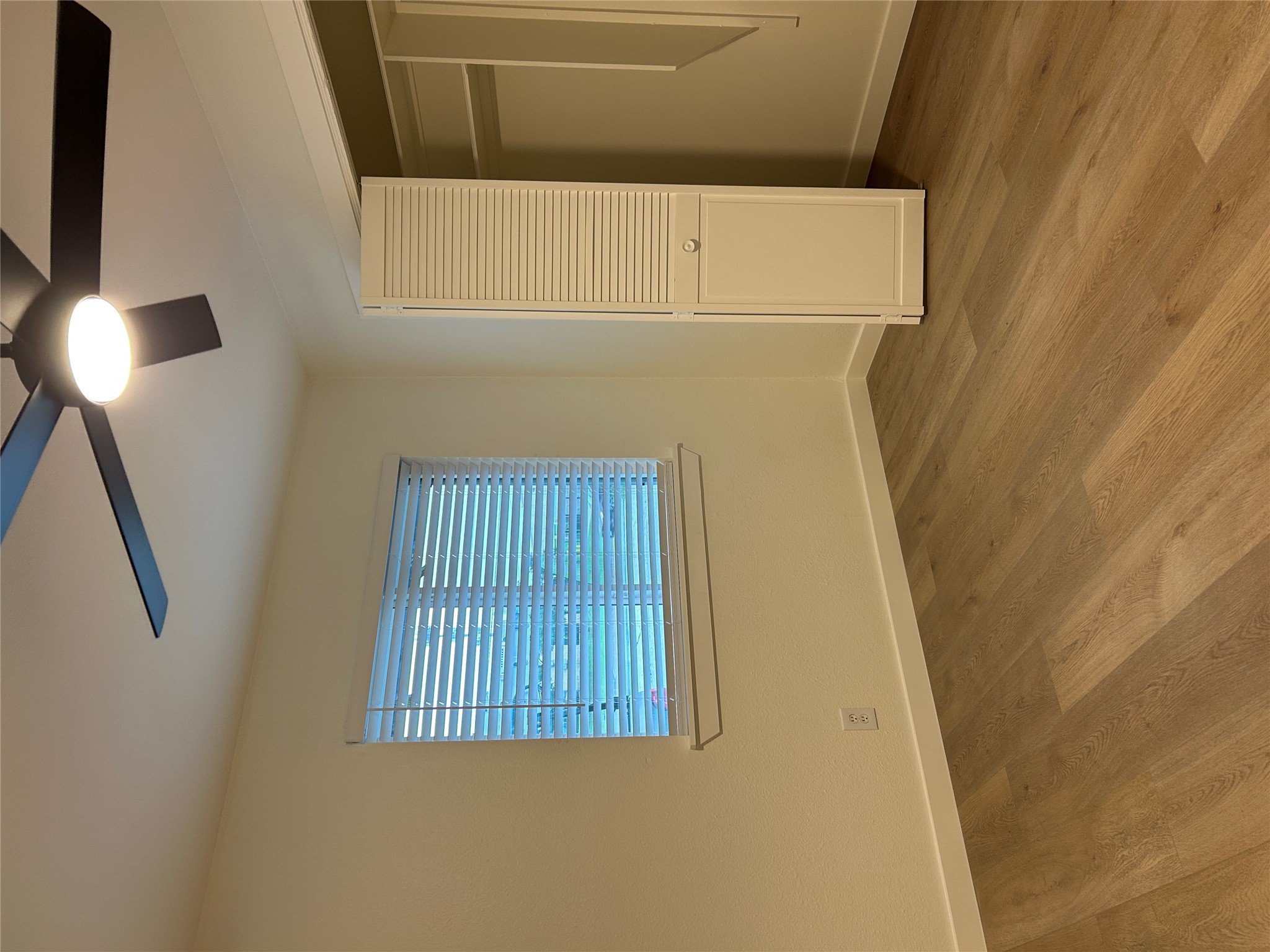 6502 South 1st Street, Unit 101 Austin, TX 78745 - Photo 10 of 12 Bedroom featuring wood-finish flooring, a ceiling fan with integrated lighting, a window with horizontal blinds, and a bi-fold louvered closet door opening to built-in shelving