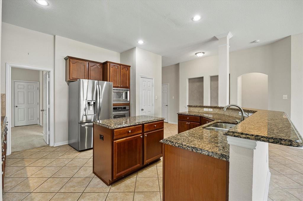 207 Leonard Way Fate, TX 75087 - Photo 15 of 31 a kitchen with granite countertop a sink and a refrigerator