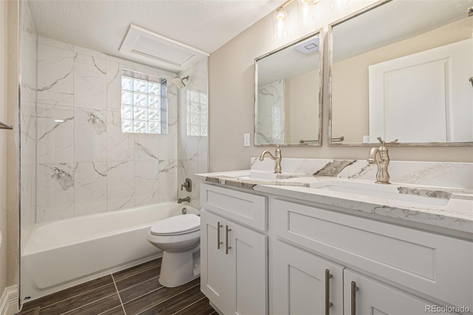 3854 Cook Street Denver, CO 80205 - Photo 25 of 42 a bathroom with a granite countertop sink a toilet and a bathtub