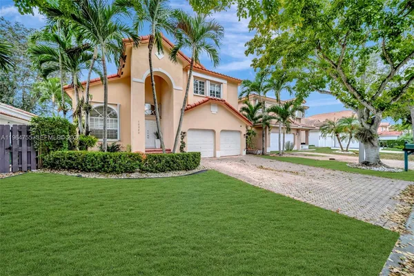 a front view of a house with a garden and tree