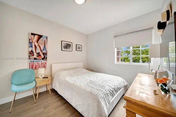 a spacious bedroom with a bed and a flat tv screen on dresser