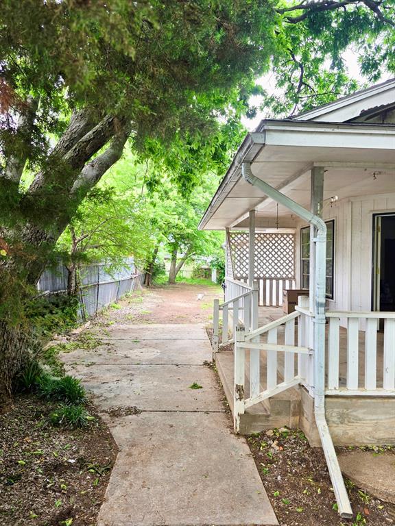 417 West Huffman Street Krum, TX 76249 - Photo 3 of 26 Covered porch with white railings and lattice detailing, featuring a concrete walkway and mature trees