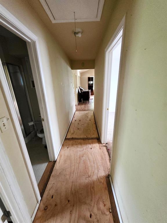 417 West Huffman Street Krum, TX 76249 - Photo 7 of 26 Hallway featuring plywood subflooring, painted walls, and a ceiling-mounted light fixture