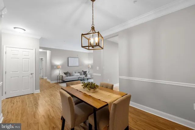 a dining room with wooden floor a chandelier a wooden table and chairs