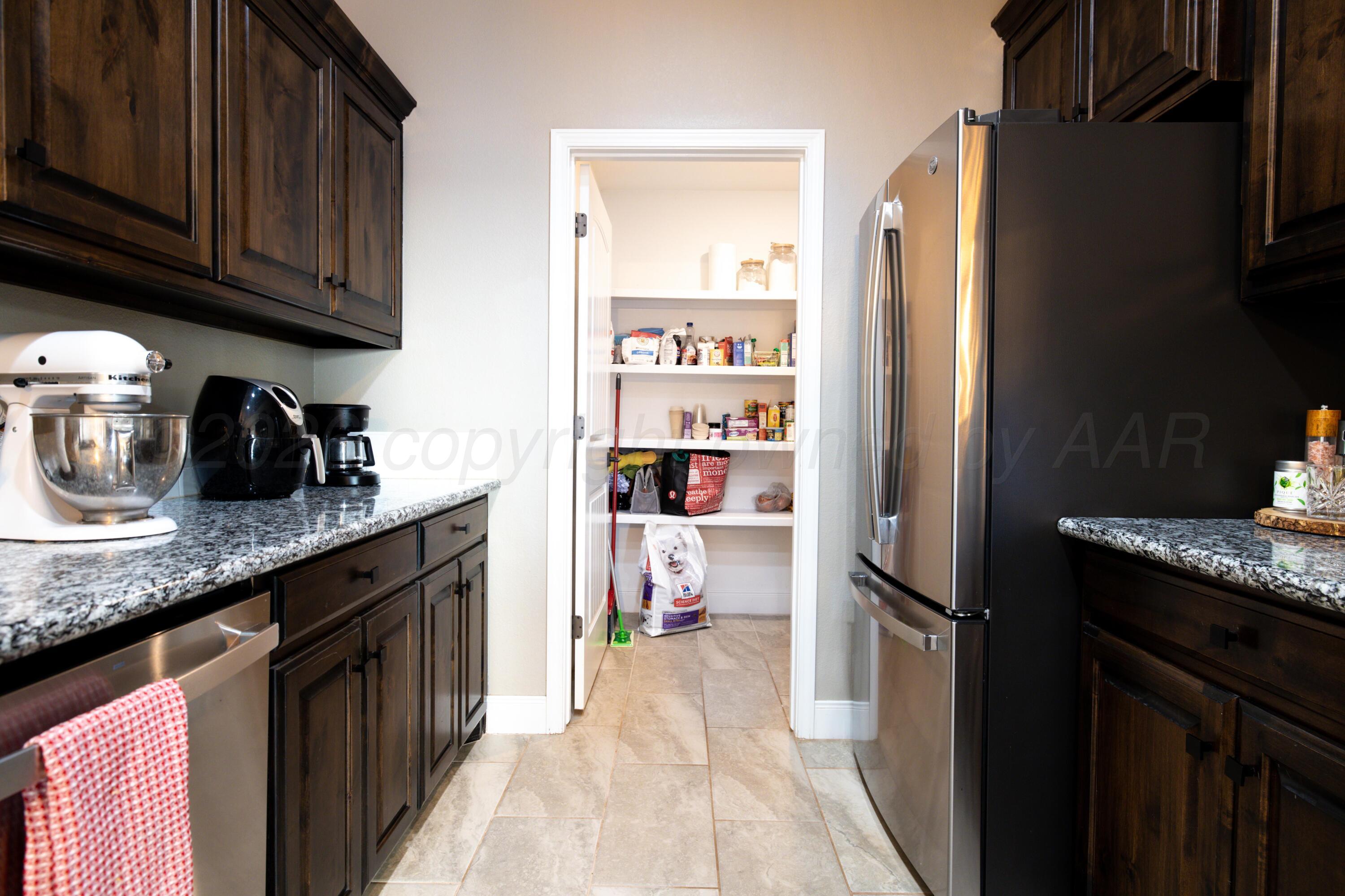 9834 Remington Road Canyon, TX 79015 - Photo 13 of 46 a kitchen with granite countertop a refrigerator a stove and wooden cabinets