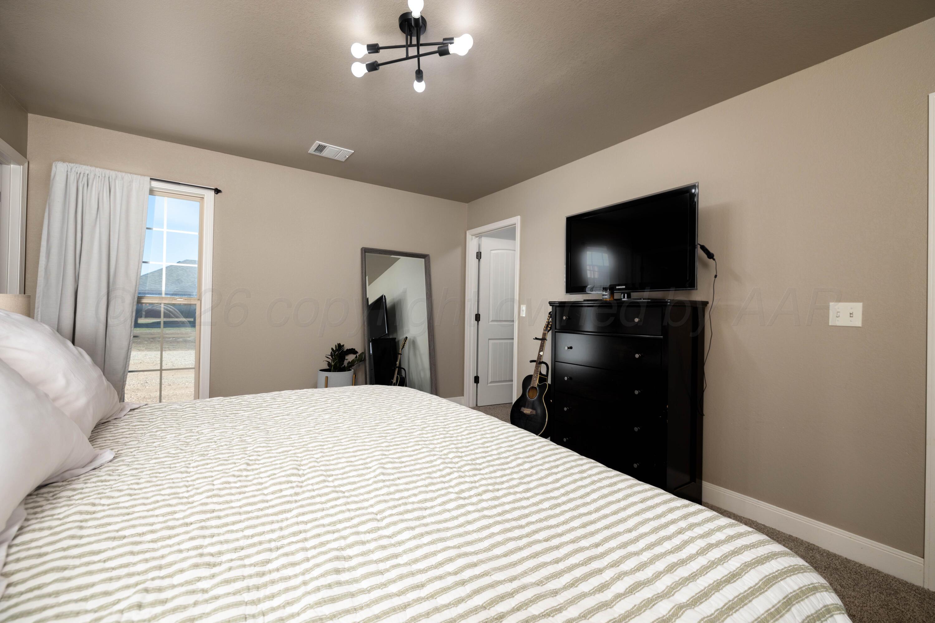 9834 Remington Road Canyon, TX 79015 - Photo 16 of 46 a bedroom with a bed and a flat screen tv