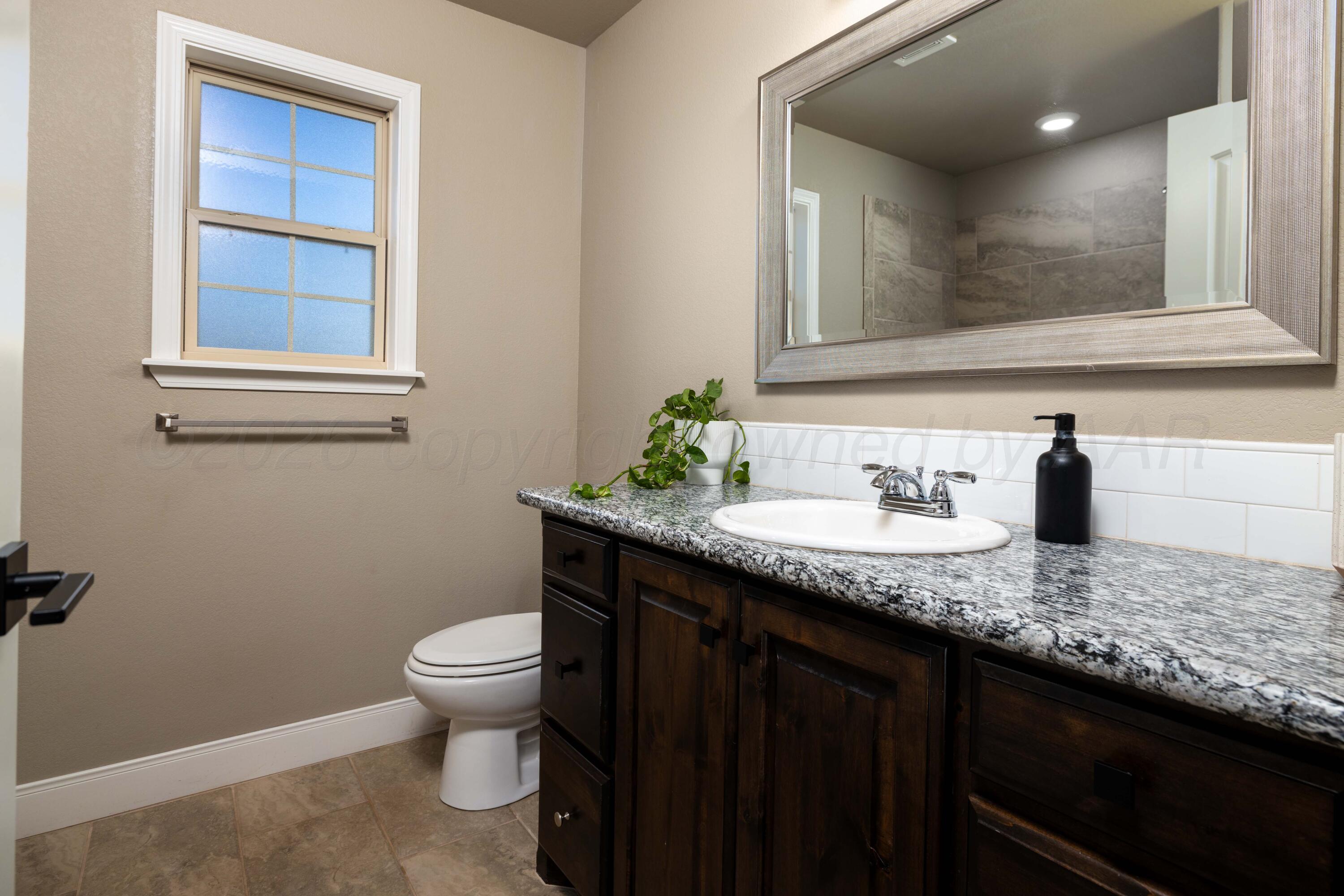 9834 Remington Road Canyon, TX 79015 - Photo 24 of 46 a bathroom with a granite countertop sink a toilet and a mirror