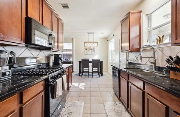 a kitchen with stainless steel appliances granite countertop a stove a sink and a microwave