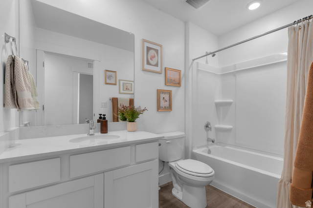 2819 South 710th West, Unit 14 Logan, UT 84321 - Photo 21 of 24 Bathroom featuring a single vanity with a white countertop and undermount sink, a large wall-mounted mirror, a tub/shower combination with a white surround, and wood-finish flooring