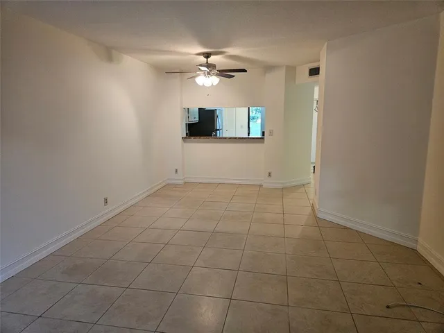 a view of an empty room with a ceiling fan and carpet