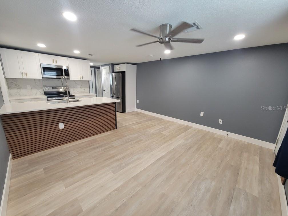 4944 Elkner Street New Port Richey, FL 34652 - Photo 5 of 24 a large kitchen with stainless steel appliances a large counter top a stove a sink dishwasher and a refrigerator with wooden floor