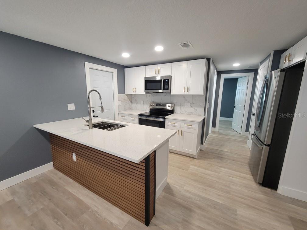 4944 Elkner Street New Port Richey, FL 34652 - Photo 6 of 24 a kitchen with stainless steel appliances a sink a refrigerator a stove a microwave and cabinets