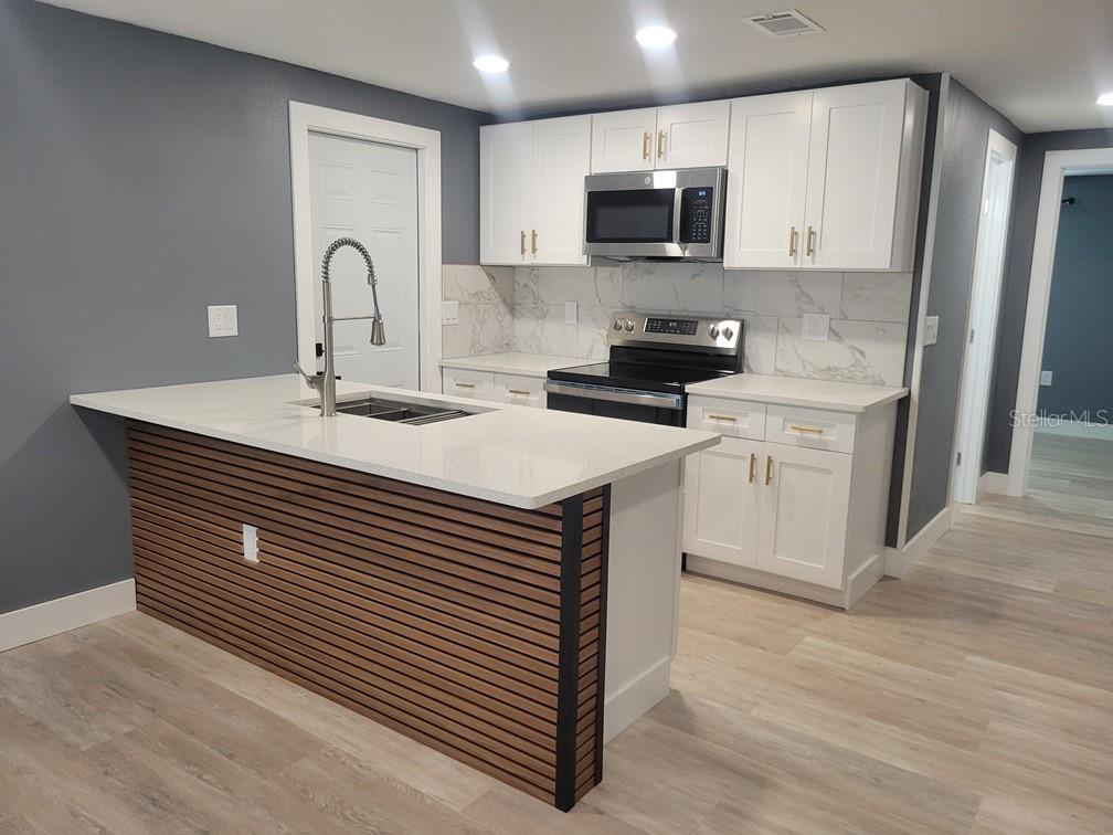 4944 Elkner Street New Port Richey, FL 34652 - Photo 7 of 24 a kitchen with a sink stove and microwave