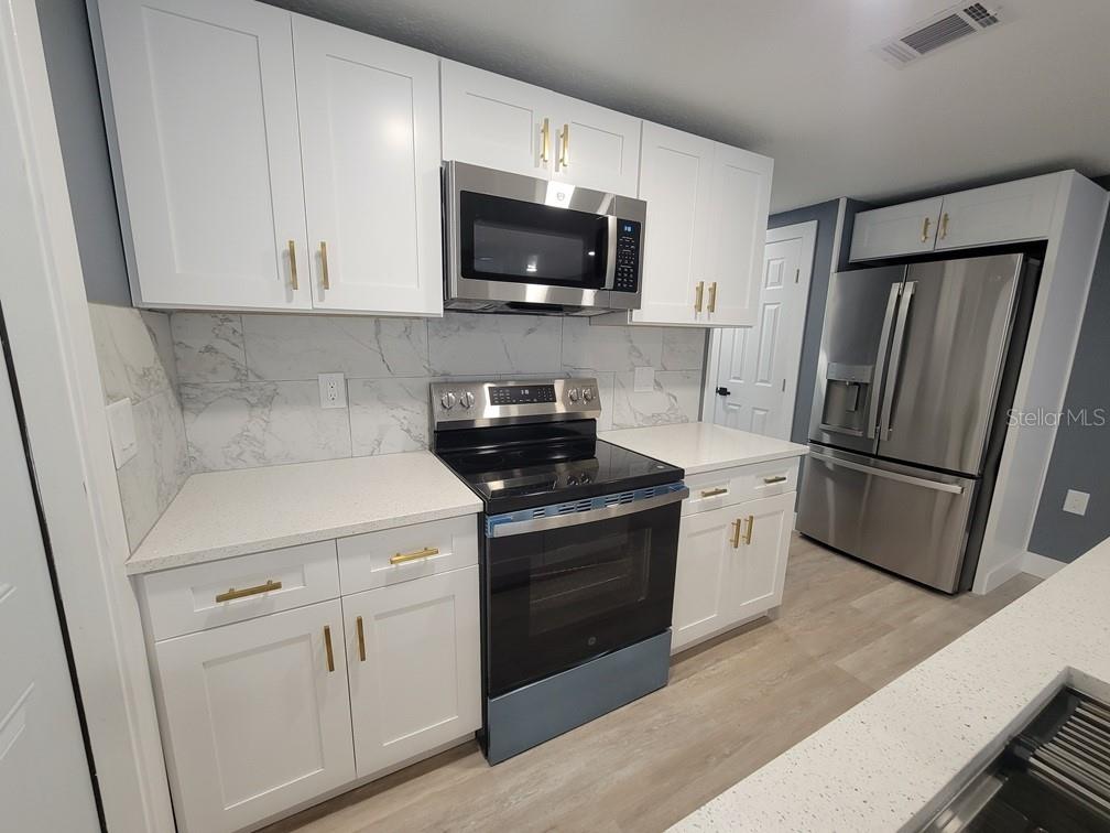 4944 Elkner Street New Port Richey, FL 34652 - Photo 8 of 24 a kitchen with stainless steel appliances white cabinets and a stove top oven