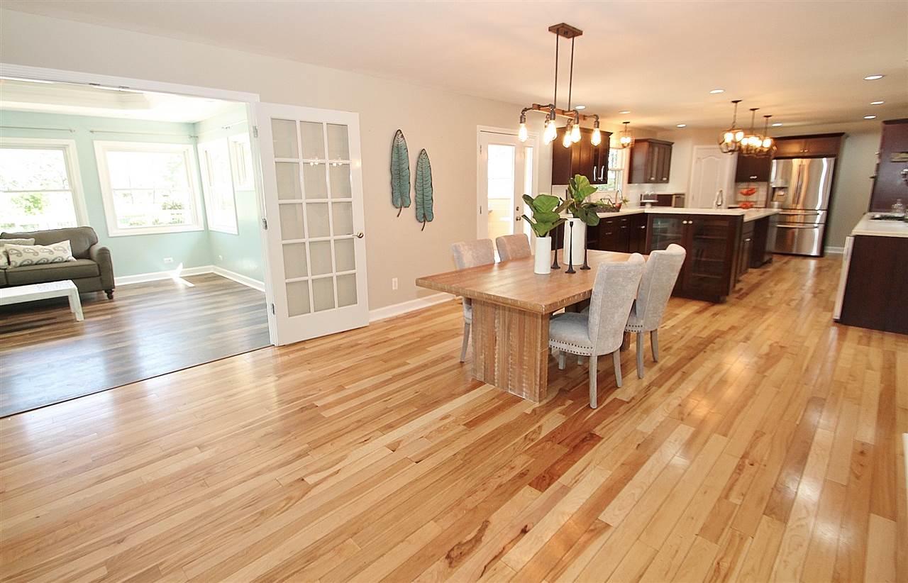 8372 Spring Creek Road Rockford, IL 61114 - Photo 5 of 25 a dining room with wooden floor a chandelier a glass table and chairs