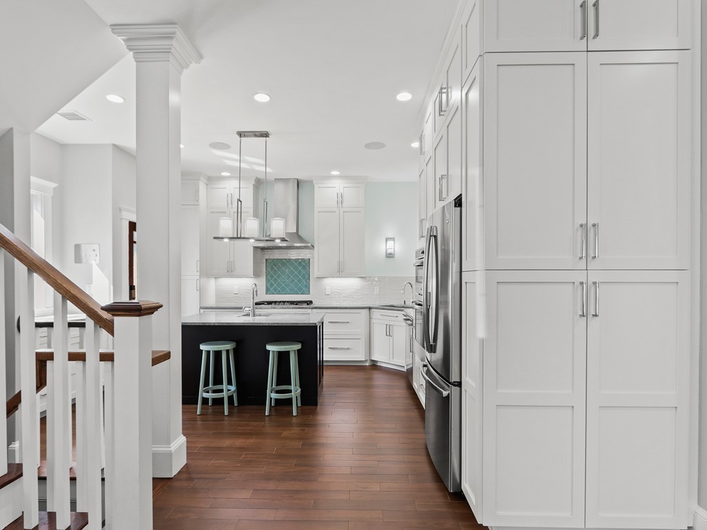 63 Herrick Road, Unit 2 Newton, MA 02459 - Photo 11 of 38 a kitchen with kitchen island wooden floors appliances and white cabinets