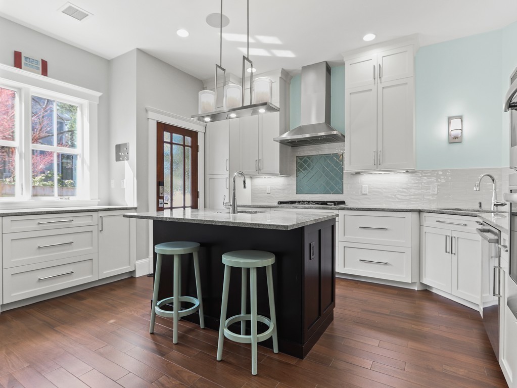 63 Herrick Road, Unit 2 Newton, MA 02459 - Photo 12 of 38 a kitchen with kitchen island granite countertop a sink cabinets and wooden floor