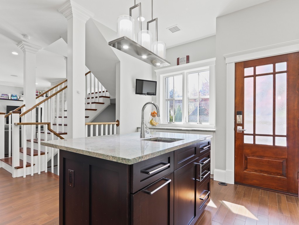 63 Herrick Road, Unit 2 Newton, MA 02459 - Photo 15 of 38 a kitchen with stainless steel appliances kitchen island a table chairs in it and wooden floors