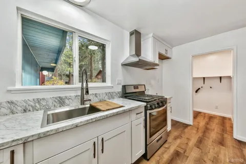 a kitchen with stainless steel appliances granite countertop a sink and a stove next to a window