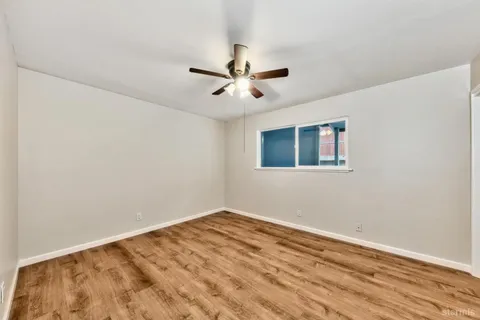a view of a big room with wooden floor and a ceiling fan