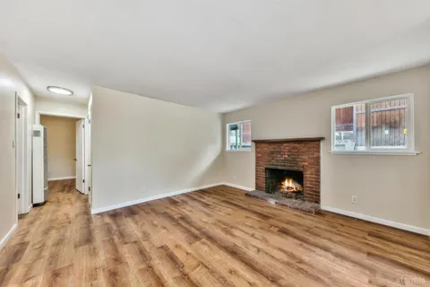 a view of empty room with wooden floor and fireplace