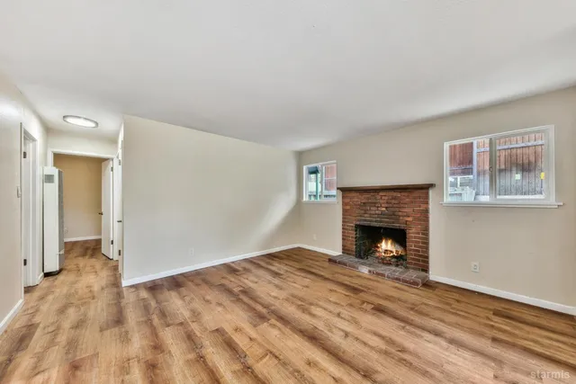 a view of empty room with wooden floor and fireplace