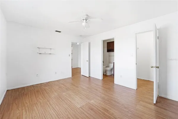 an empty room with wooden floor and a ceiling fan