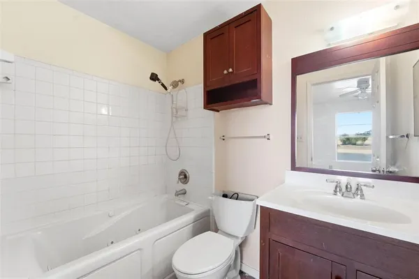 a bathroom with a toilet a sink a mirror a bathtub and vanity