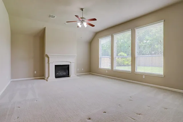 an empty room with chandelier fan and windows