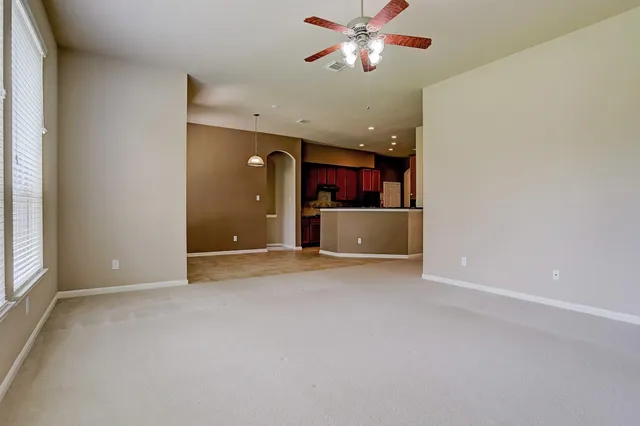 an empty room with chandelier fan and windows