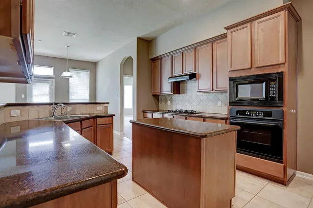 a kitchen with stainless steel appliances granite countertop a stove a sink and a microwave