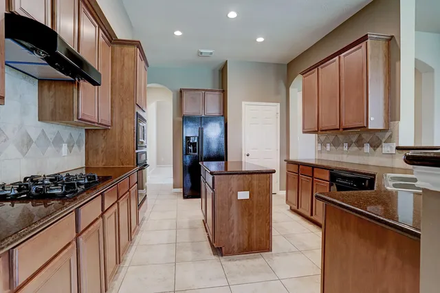 a kitchen with stainless steel appliances granite countertop a stove a sink and a refrigerator