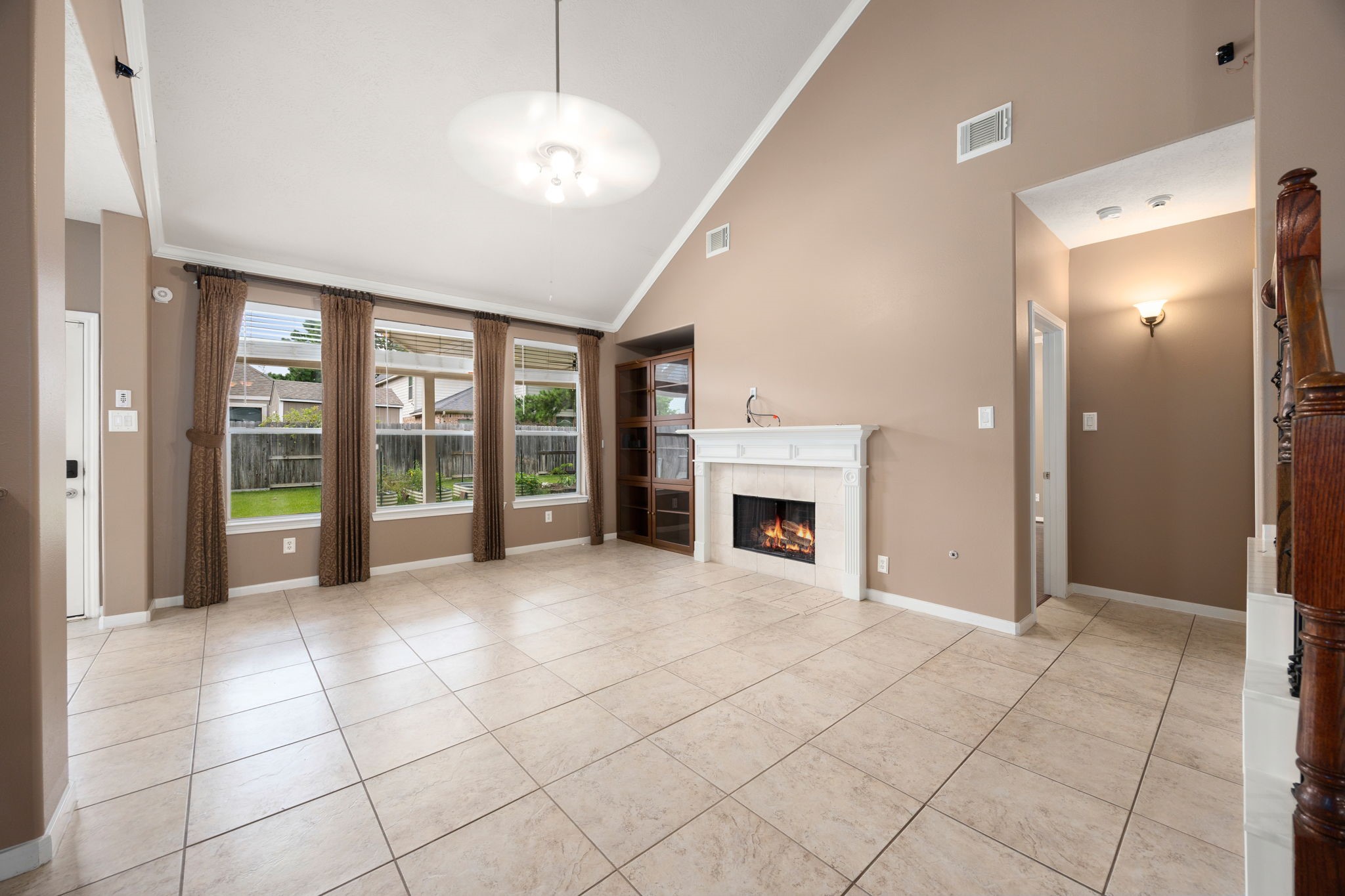 4526 Countrypines Drive Spring, TX 77388 - Photo 13 of 38 Impressive family room boasting dramatic vaulted ceilings, low-maintenance tile flooring, and a bank of large windows looking out to the backyard. A cozy fireplace with a classic white mantel serves as the perfect centerpiece for gathering.