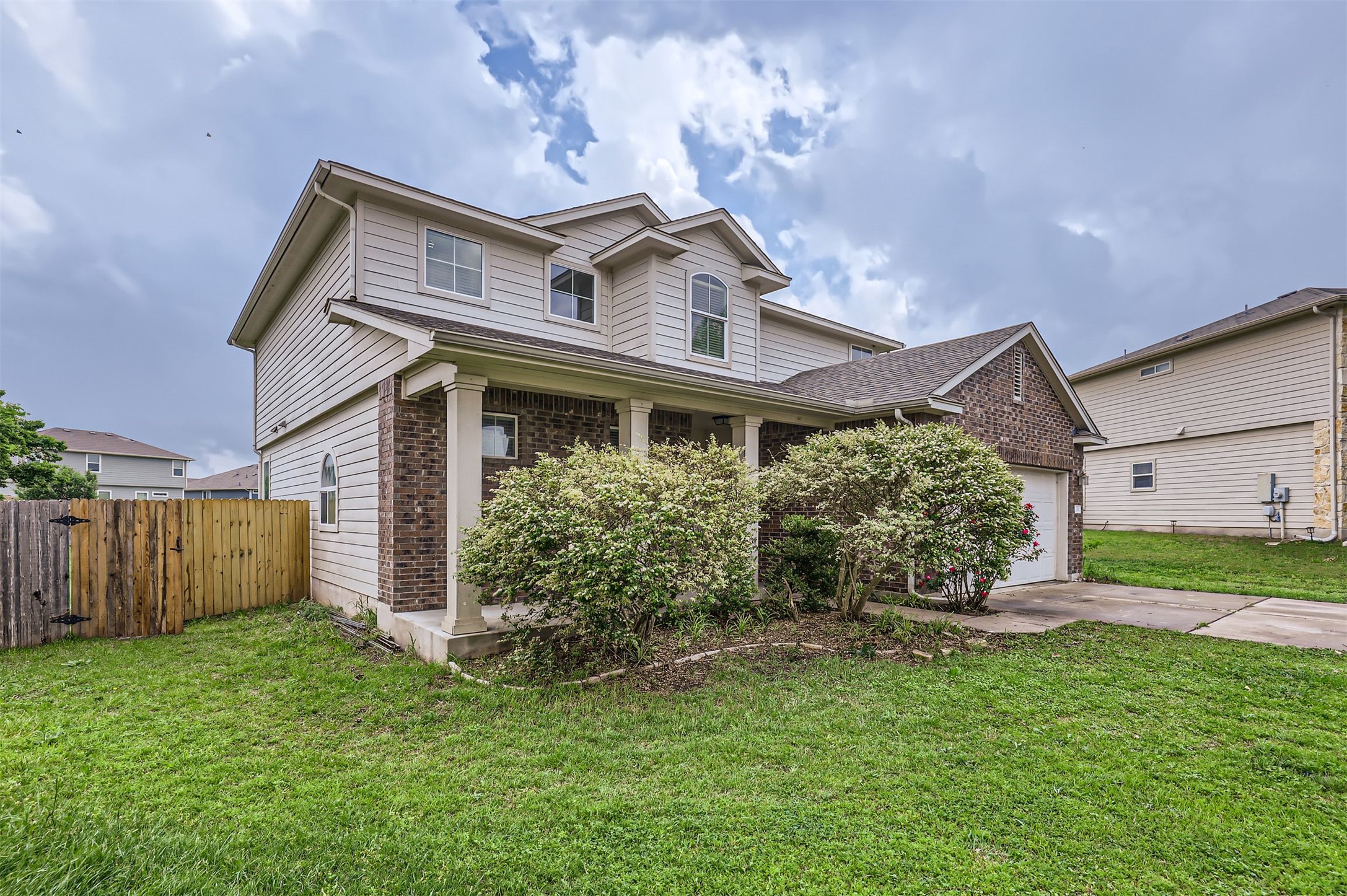 131 Lavaca Loop Hutto, TX 78634 - Photo 3 of 29 A classic front facade features a welcoming covered porch, mature shrubs, and an attached garage.