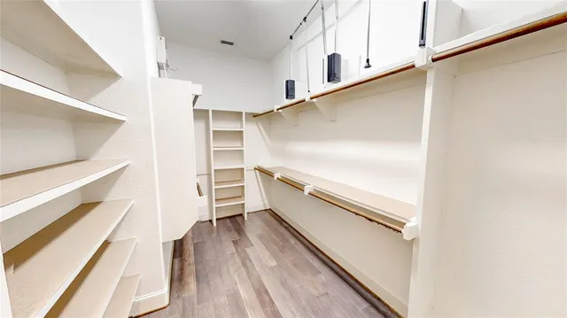 a view of walk in closet with wooden floor and a window