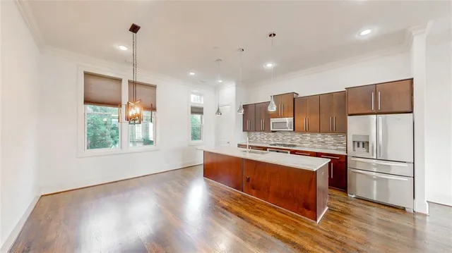 a kitchen with stainless steel appliances granite countertop a stove a refrigerator a sink and a oven with wooden floor