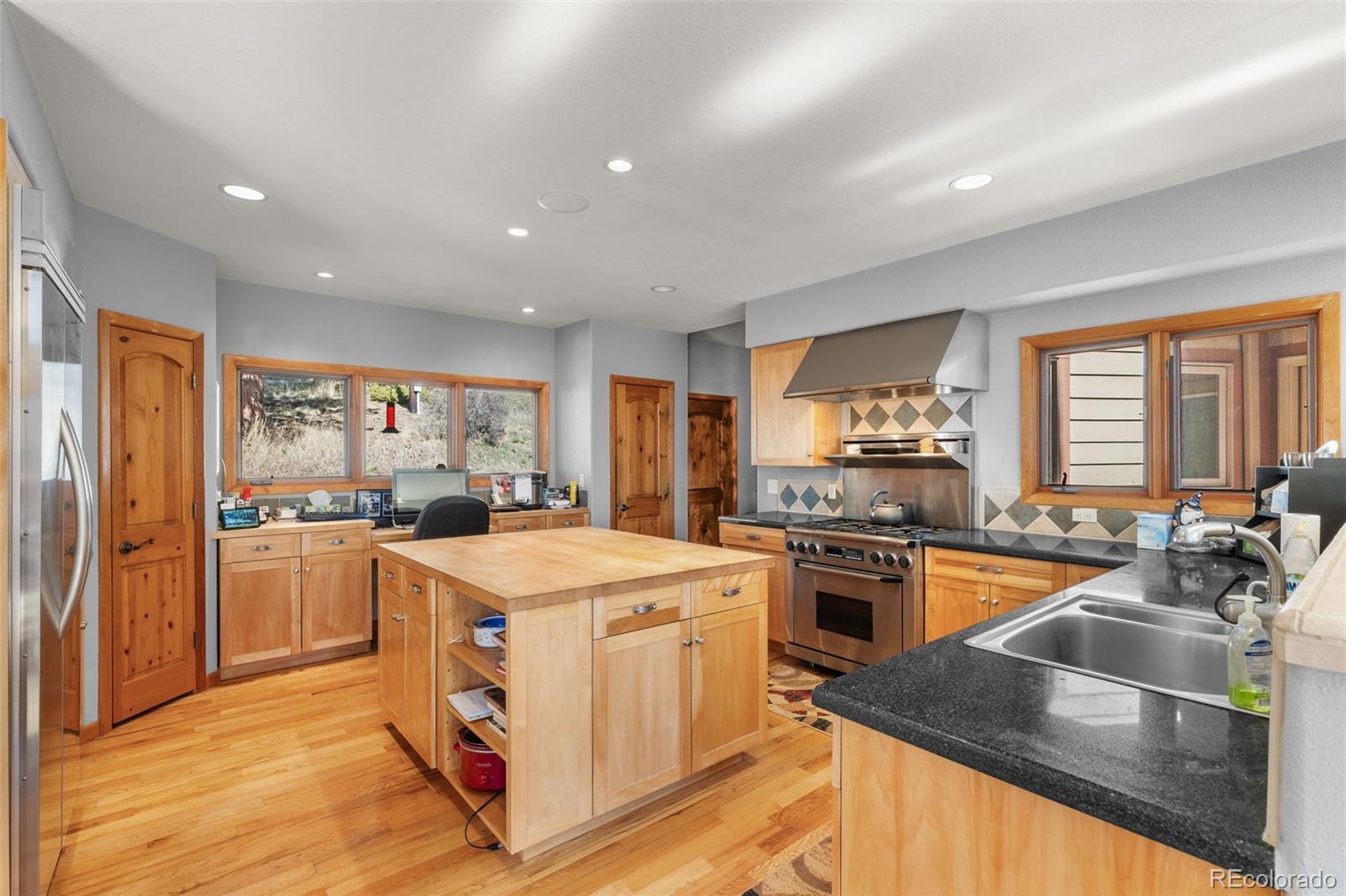 13445 Baird Road Conifer, CO 80433 - Photo 16 of 50 a kitchen with stainless steel appliances granite countertop a stove top oven a refrigerator a sink and dishwasher with wooden floor