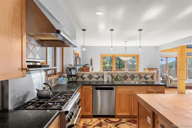 a kitchen with a stove a sink a window and dining table