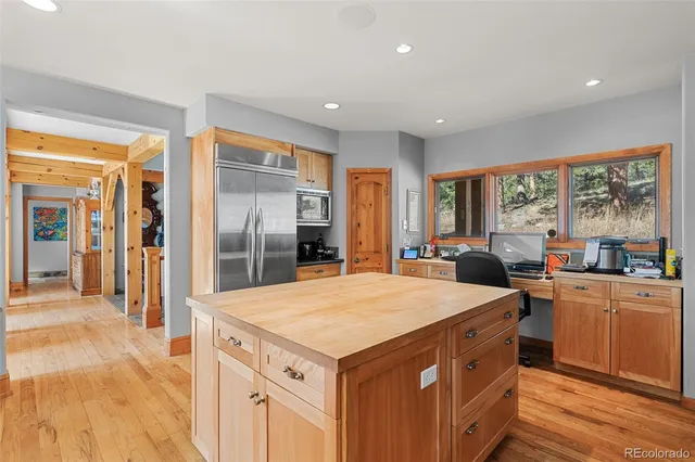 a kitchen with stainless steel appliances kitchen island granite countertop a refrigerator a stove top oven and a view of living room