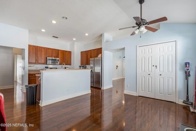 a kitchen with stainless steel appliances granite countertop wooden cabinets a stove a sink and dishwasher with wooden floor