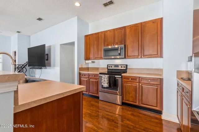 a kitchen with stainless steel appliances granite countertop a stove a sink dishwasher and a refrigerator with wooden floor