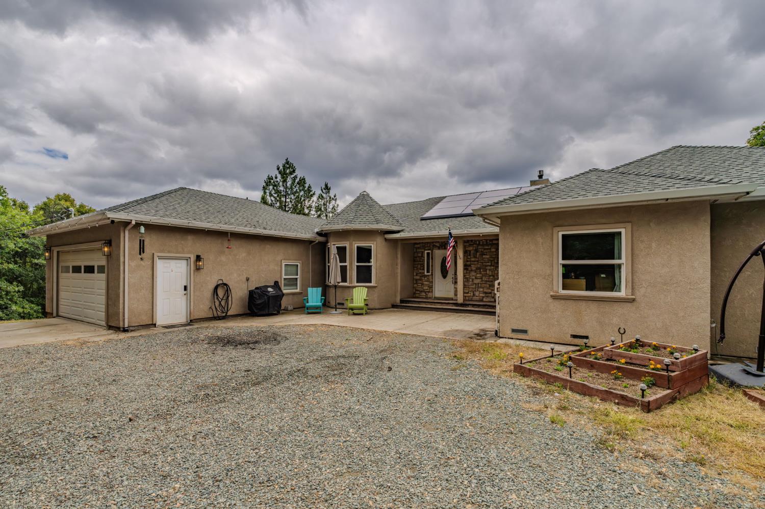Stucco exterior residence featuring a gravel driveway and an attached two-car garage