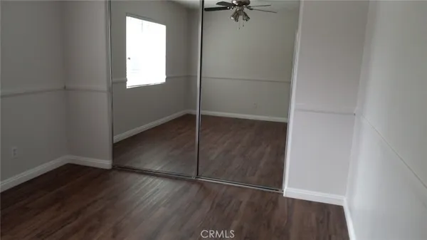 an empty room with wooden floor closet and windows