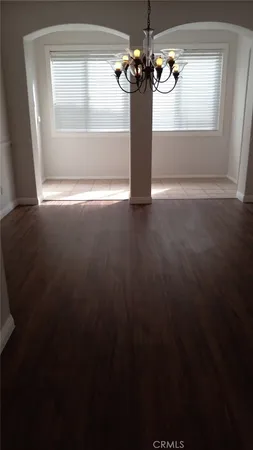 a view of a room with wooden floor chandelier and windows