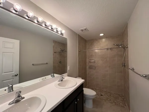 a bathroom with a sink a toilet a mirror and shower